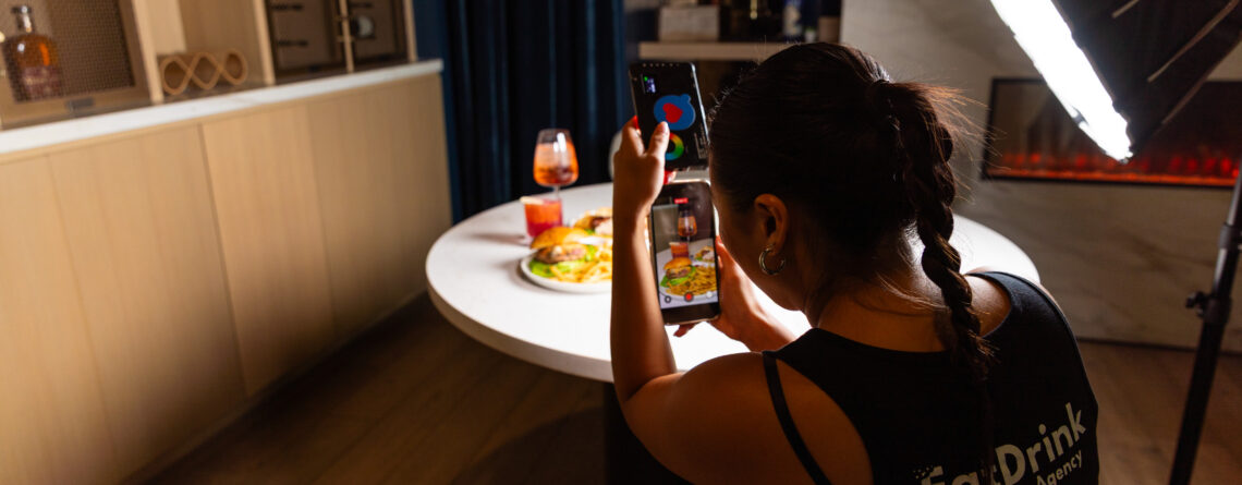EDC Agency team member filming a burger, fries, and spritz with a phone and softbox light