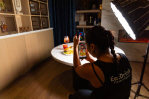 EDCBTS-2 EDC Agency team member filming a burger, fries, and spritz with a phone and softbox light