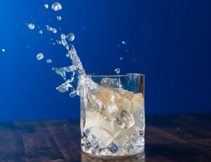 EDCBrandingCocktails-58 Water splashing into a crystal rocks glass of ice against a deep blue background