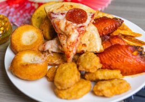 Lins-May2026-29 Pepperoni pizza slice, buffalo wings, chicken nuggets, and fried bites piled on a plate at Lin's Grand Buffet in Phoenix, Arizona